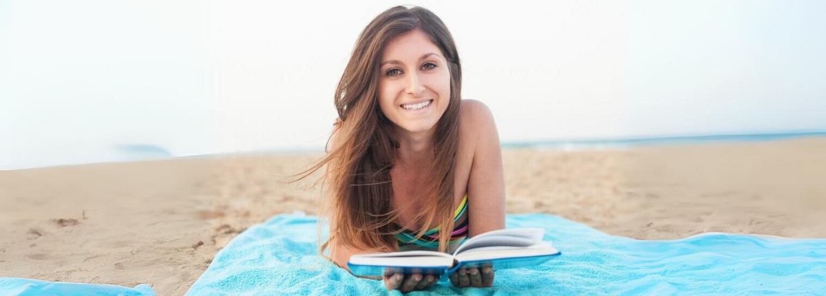 Bookcrossing d'estate, una ragazza legge sulla spiaggia