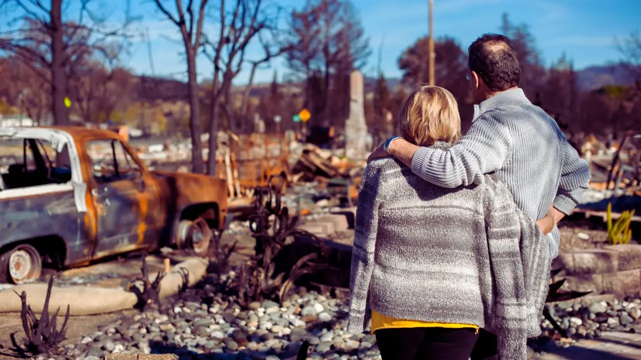 Coppia davanti alla casa in fiamme. Foto: Canva