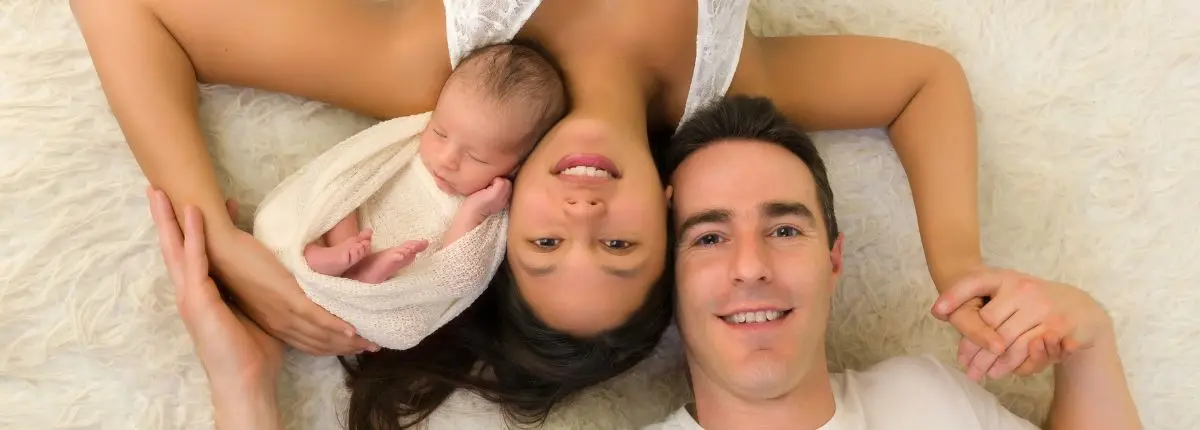 Una mamma, un papà e il loro neonato sul letto