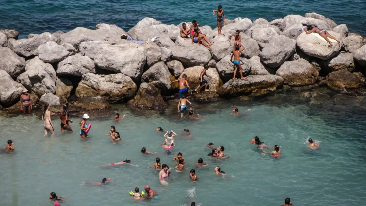 Ad agosto ascolta la natura: una scogliera con molti bagnanti