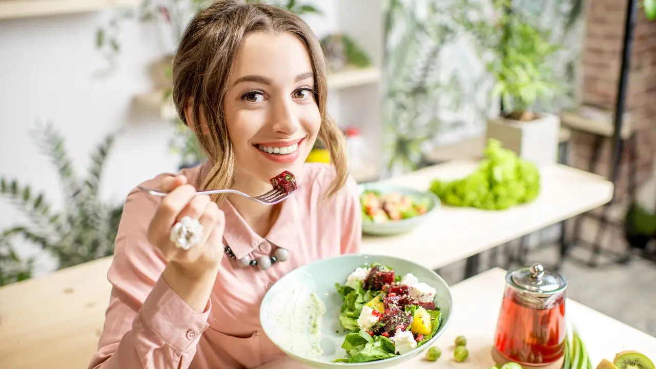 La Dieta Med ha una nuova piramide: una ragazza mangia sorridendo della verdura