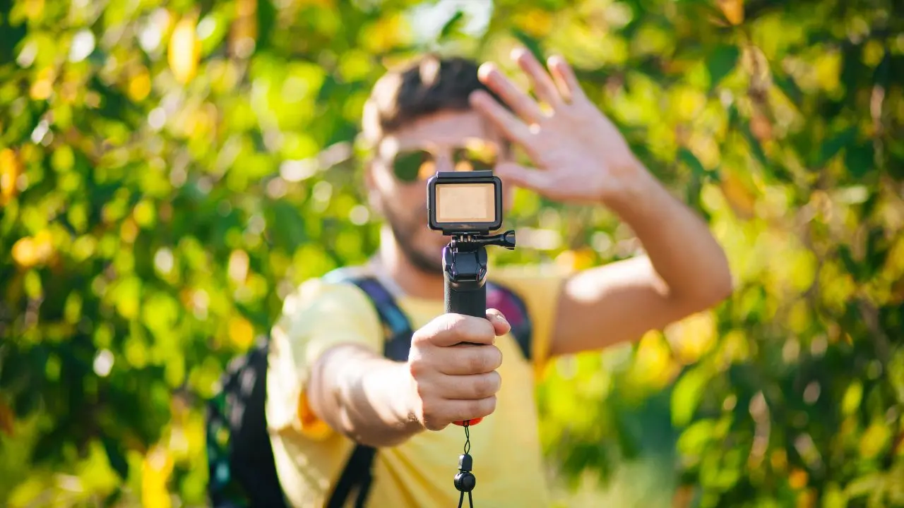 Un'estate da eco-influencer: un ragazzo registra un video con una action camera in uno spazio naturale