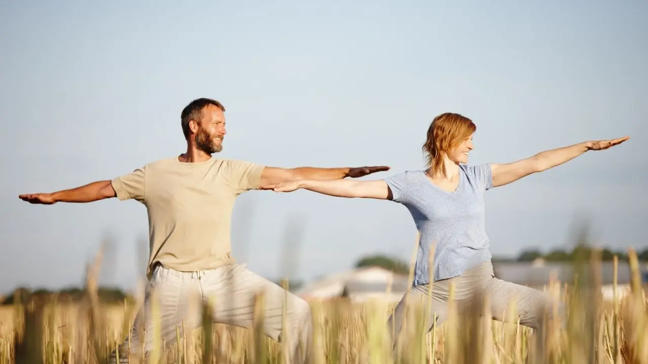 Semi e germogli: una donna e un uomo Due persone praticano yoga all’aperto in un campo di grano
