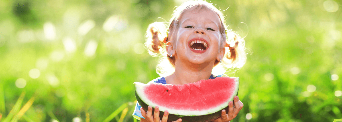 bimba che ride con in mano una fetta di anguria. mangiare frutta per una estate in sicurezza