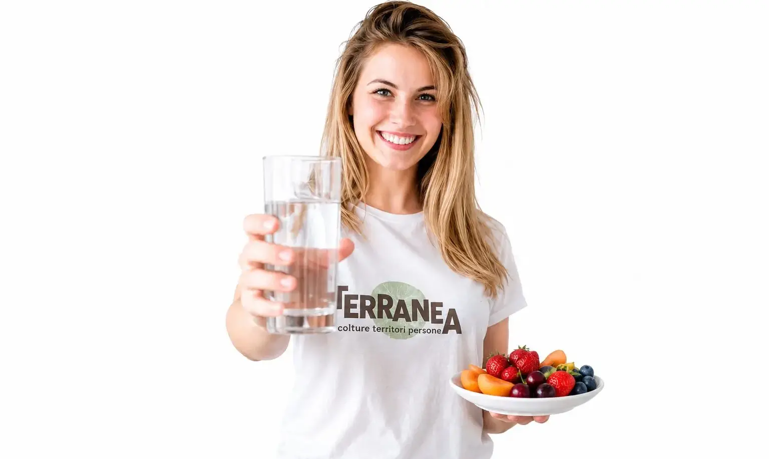 Donna sorridente con bicchiere d'acqua, frutta estiva e maglietta Terranea, simbolo di benessere.